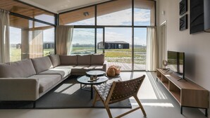 Una sala de estar moderna con un sofá seccional, una mesa de centro, una silla y un televisor sobre un mueble.