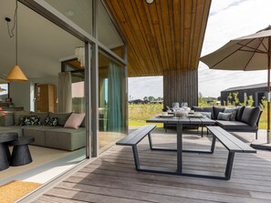 A modern outdoor patio with a dining table, seating, and a view of the surrounding landscape. - Nature house with views over fields (Wissenkerke)