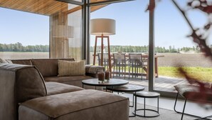 Ein modernes Interieur mit einem großen Fenster, einem Sofa, einem Tisch und einer Lampe.