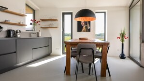 Eine moderne Küche mit Essbereich, einem großen Fenster und einer Pendelleuchte.
