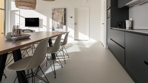 A modern kitchen with a dining area, featuring a wooden table, white chairs, and a large window. - Nature house with 2 bathrooms (Wissenkerke)