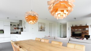 Una cocina moderna con armarios blancos, una mesa de comedor de madera y dos lámparas colgantes.