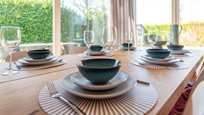 A dining table set with blue bowls, wine glasses, and plates, with a star decoration above the table. - Holiday home on Lake Veere (Kamperland)