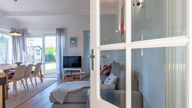 A modern living room with a sofa, TV, and dining area. - Holiday home on Lake Veere (Kamperland)