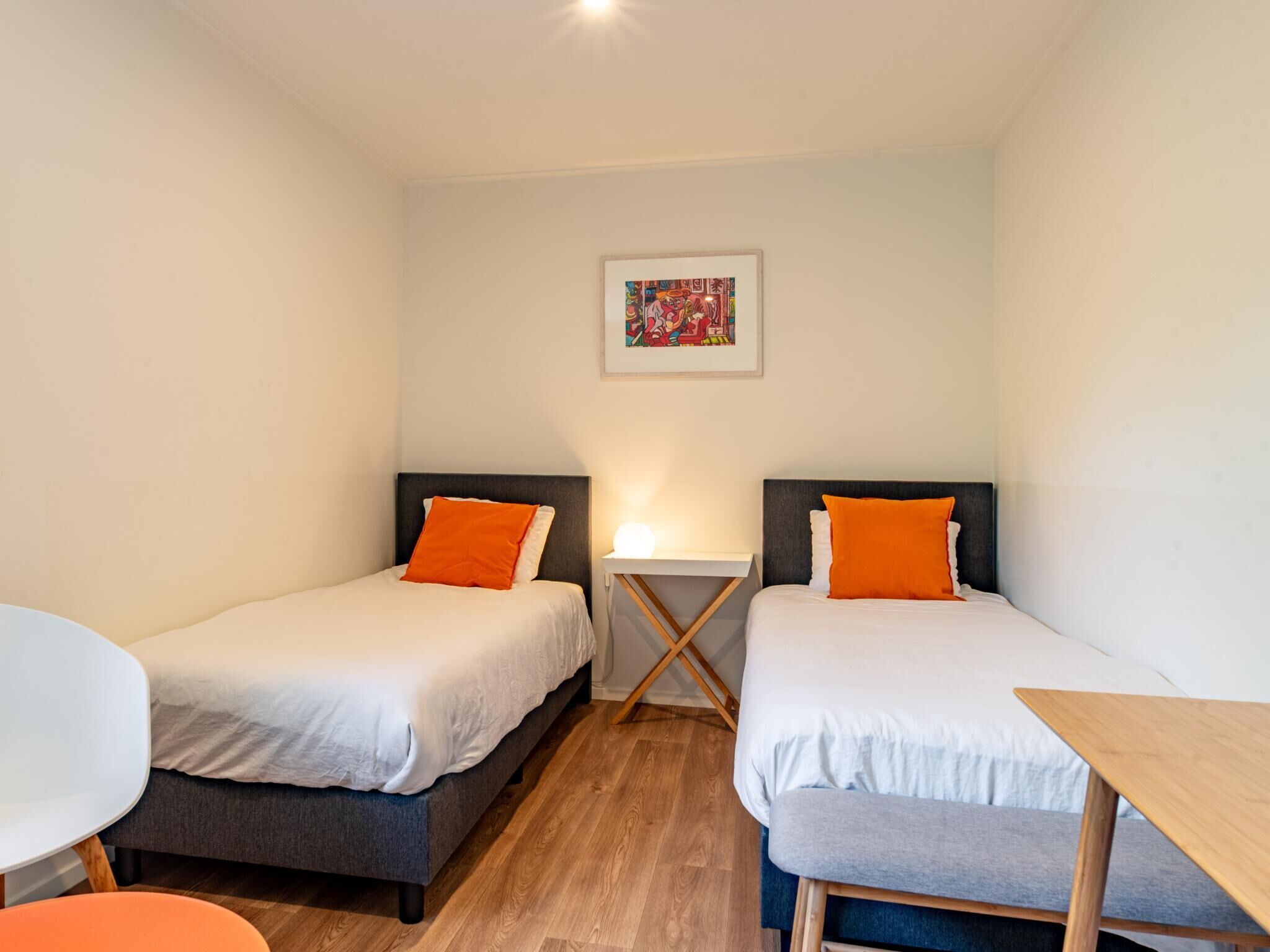 Una habitación con dos camas, una mesita y una silla.