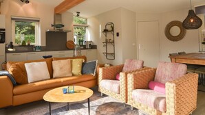 Ein modernes Wohnzimmer mit einer Couch, Sesseln, einem Couchtisch und einem Essbereich.
