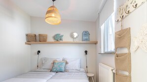 Ein Schlafzimmer mit Bett, einer Pendelleuchte, einem Regal mit Dekoration und einem Fenster mit Blick.