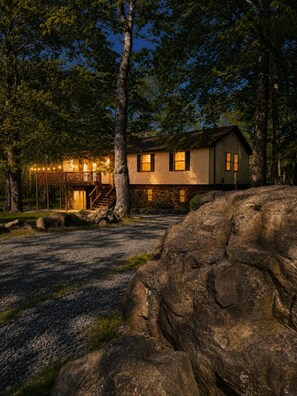 Eine rustikale Holzhütte mit einer Holzdiele, einem Steinpfad und großen Felsen.