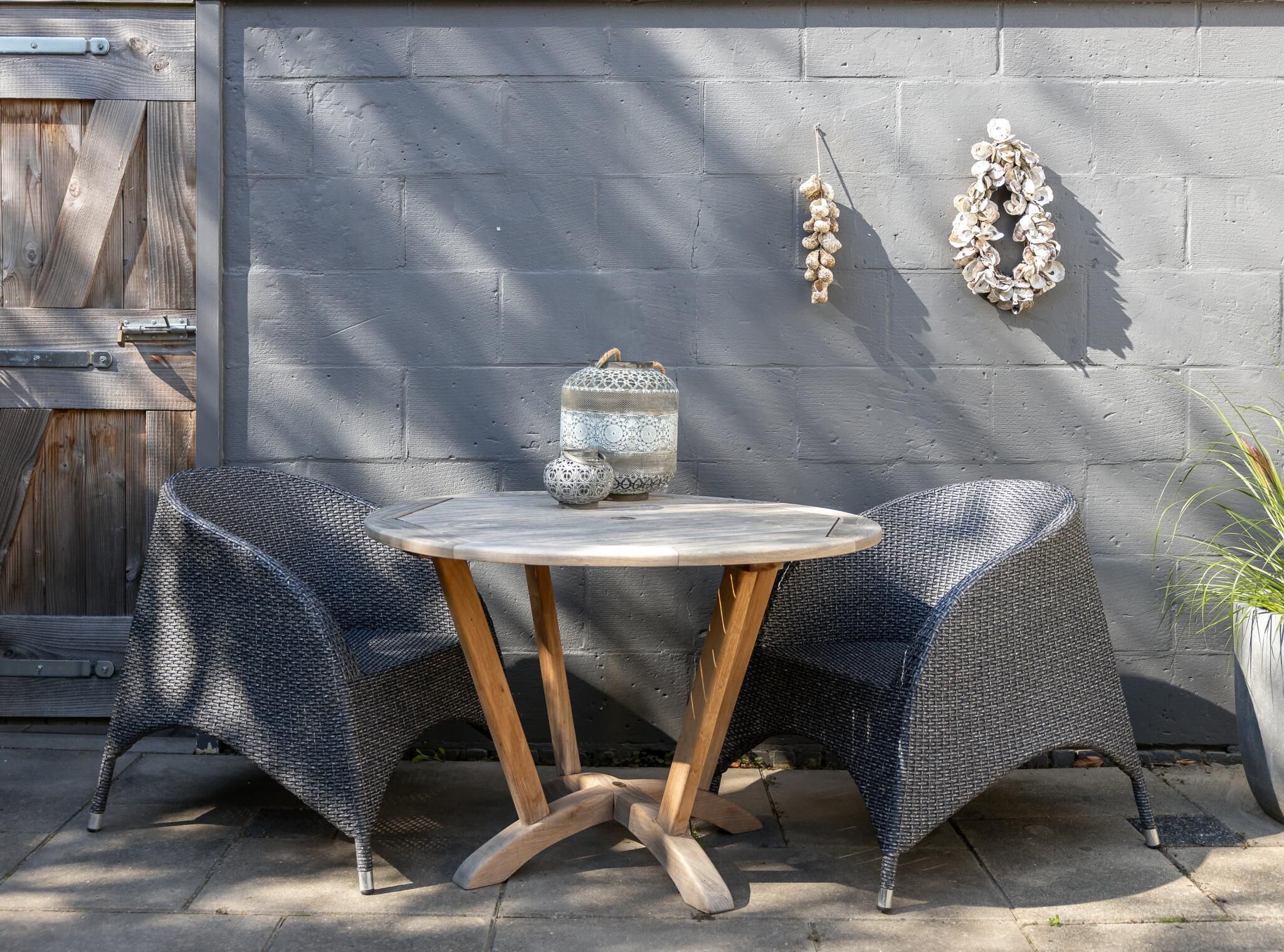 A round table with a woven chair on each side, a decorative lantern, and a wall-mounted garland.