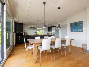 A modern kitchen with a dining area, large windows, and a view of greenery. - Spaciously designed home by Veerse Meer. (Kamperland)