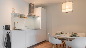 A modern kitchen with white cabinetry, a built-in stove, and a dining area with a white table and chairs. - Nice, light apartment with a terrace. (Kamperland)