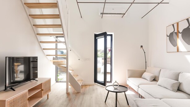 A modern living room with a TV, sofa, and staircase. - Nice, light apartment with a terrace. (Kamperland)