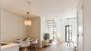 A modern interior with a dining area, a staircase, and a TV. - Nice, light apartment with a terrace. (Kamperland)
