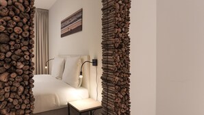 Un dormitorio con cama, mesita de noche, lámpara y un cuadro en la pared.