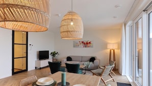 Una sala de estar moderna con comedor, ventanas amplias y un televisor.