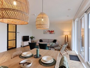 A modern living room with a dining area, large windows, and a television. - Modern apartment with balcony by the harbor (Kamperland)