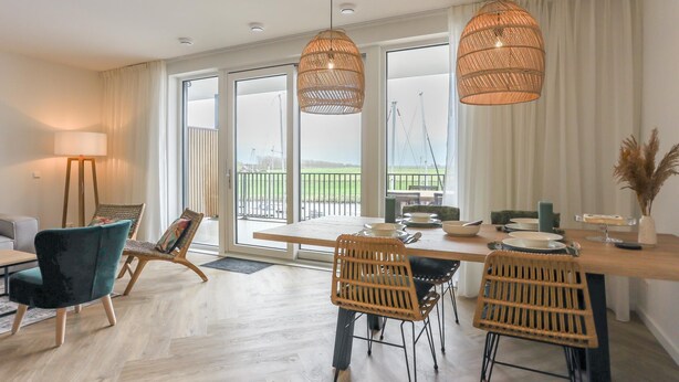 Un comedor moderno con una mesa de madera, sillas de mimbre e iluminación colgante.
