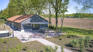 A house with a patio, outdoor seating, and a view of a field.