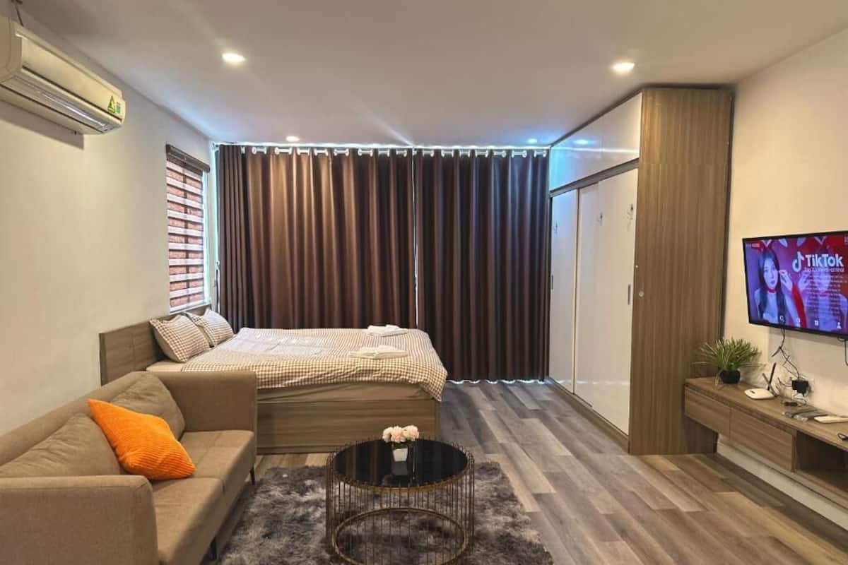 Een moderne slaapkamer met een bed, een bank, een salontafel, een televisie en een kledingkast.