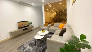 Un salon moderne comprenant un canapé, deux tables basses, un téléviseur et un élément de séparation décoratif.