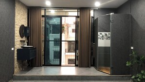 Une chambre moderne dotée d’une porte-fenêtre coulissante donnant sur un balcon, d’un téléviseur intégré et d’un réfrigérateur.