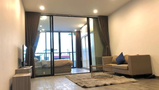 Un salon moderne avec un canapé, une table basse et une porte-fenêtre coulissante donnant sur un balcon.