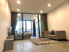 Una sala de estar moderna con un sofá, una mesa de centro y un ventanal corredero que da a un balcón.