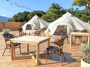 A wooden deck with a table and chairs, surrounded by tents. - Komatsushima Resort (Tokushima)