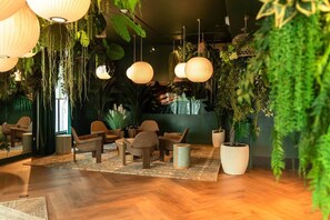 Ein Zimmer mit Holzböden, Korbmöbeln, hängenden Pflanzen und Pendelleuchten.