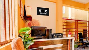 Ein Hotelrezeptionstresen mit Computer, Drucker und einem Schild mit der Aufschrift 'HOTEL Company-Serviced'.