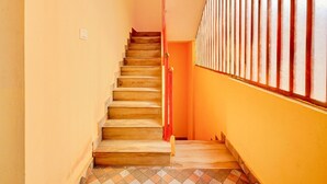 Eine Treppe mit Holzstufen, die nach oben führt, gesäumt von gelben Wänden und einem Fenster mit vertikalen Streben.