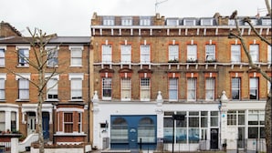 Une rangée de maisons mitoyennes avec une porte de garage bleue, des éléments décoratifs blancs et une façade en briques.