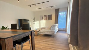 A modern living room with a wooden dining table, a sofa, and a TV. - Family-friendly with garden & private parking lot Suitable for fitters & groups (Oldenburg (Oldb))