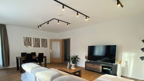 A modern living room with a sofa, television, and dining area. - Family-friendly with garden & private parking lot Suitable for fitters & groups (Oldenburg (Oldb))