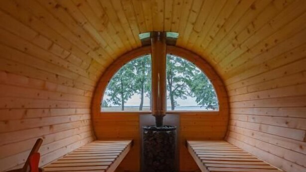 A wooden cabin with a sloped ceiling, a central chimney, and a window at the end. - Mazurskie Domy Nad Kisajnem (Giżycko)