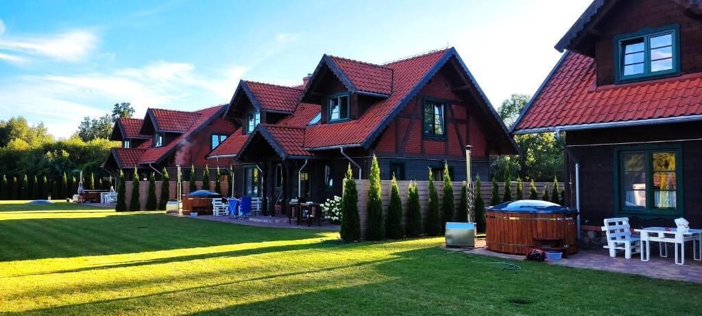 Una hilera de casas de madera con techos rojos, un césped bien cuidado y mobiliario de exterior.