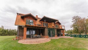 A two-story house with a balcony, a patio with outdoor furniture, and a well-maintained lawn. - Mazurskie Domy Nad Kisajnem (Giżycko)