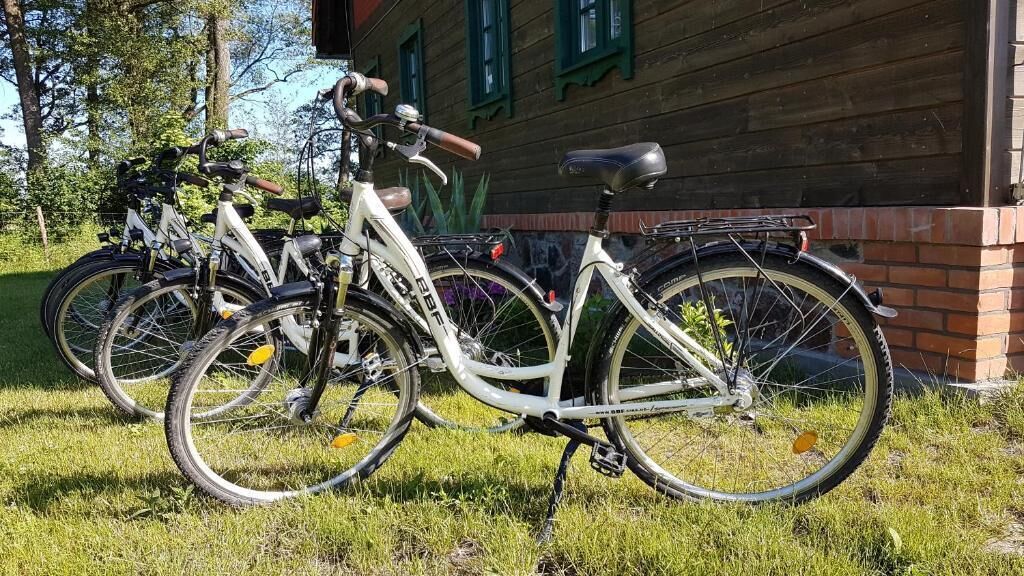 A bicycle parked on grass in front of a building with a brick base and green windows.