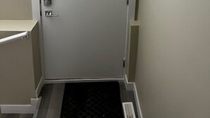 Una puerta con un teclado electrónico, una pequeña rejilla de ventilación y un interruptor de luz en la pared.