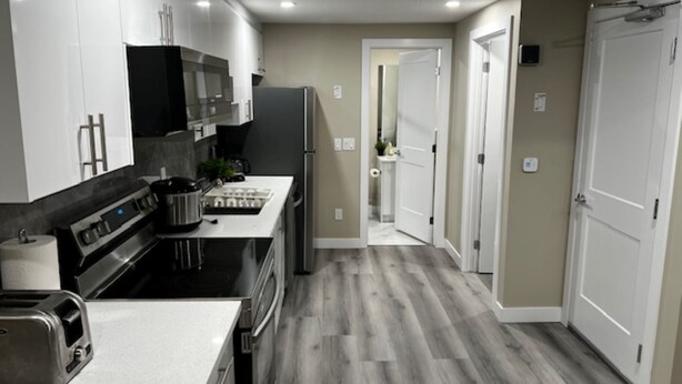 Una cocina moderna con armarios blancos, estufa de acero inoxidable y microondas integrado.
