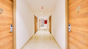 Un long couloir étroit, bordé de portes en bois numérotées 104 et 108, qui donnent accès à des pièces.