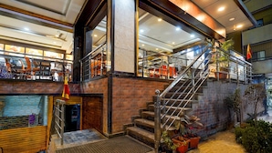 Un intérieur d’hôtel à plusieurs niveaux, comprenant un escalier, un espace salon et une vue sur le restaurant.