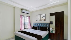 Une chambre à coucher comprenant un lit, une fenêtre avec des rideaux, un appareil de climatisation et une armoire.
