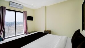 Une chambre d’hôtel avec un grand lit, un appareil de climatisation, une télévision et une fenêtre avec des rideaux.