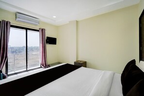 A hotel room with a large bed, an air conditioning unit, a television, and a window with curtains. - Hotel O Ring Road Nagpur (Nagpur)