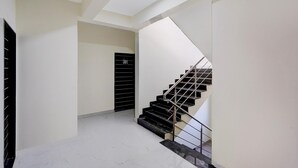 Un intérieur moderne avec un escalier, une porte portant un numéro et un sol carrelé, propre et bien entretenu.