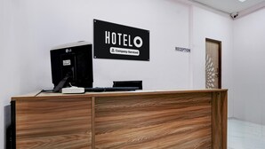 Un comptoir d’accueil avec une pancarte indiquant « HOTELO, services d’entreprise » et une autre pancarte, « RÉCEPTION », affichée sur le mur.