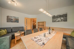 A modern living room with a sofa, dining table, and artwork on the walls. - Apartment in Brixen Near Wilder Kaiser Gondola (Brixen im Thale)