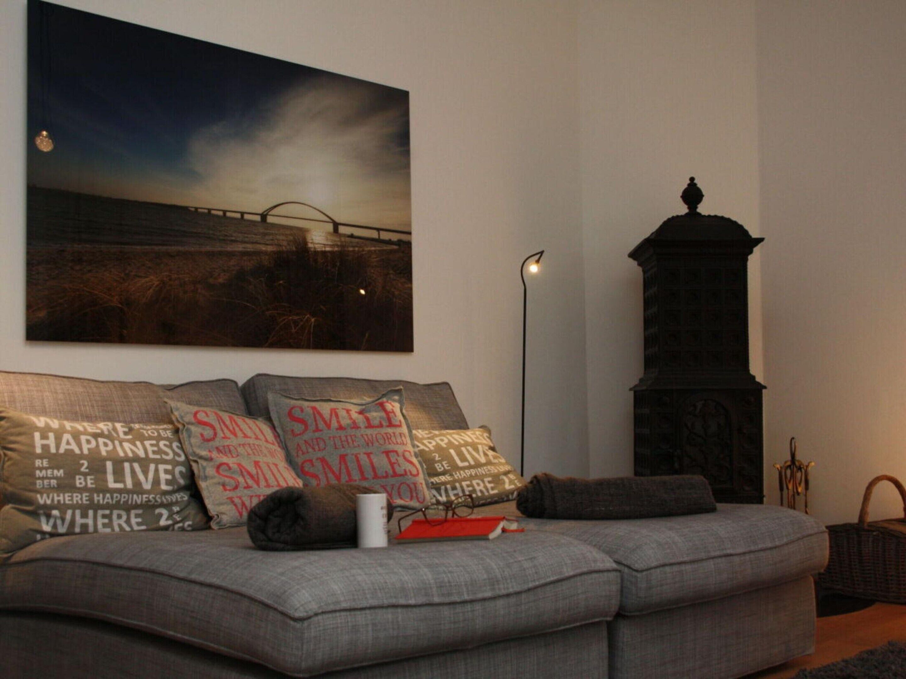 Ein Wohnzimmer mit grauem Sofa, einem großen Wandbild und einer hohen, dunklen Holzkonstruktion.