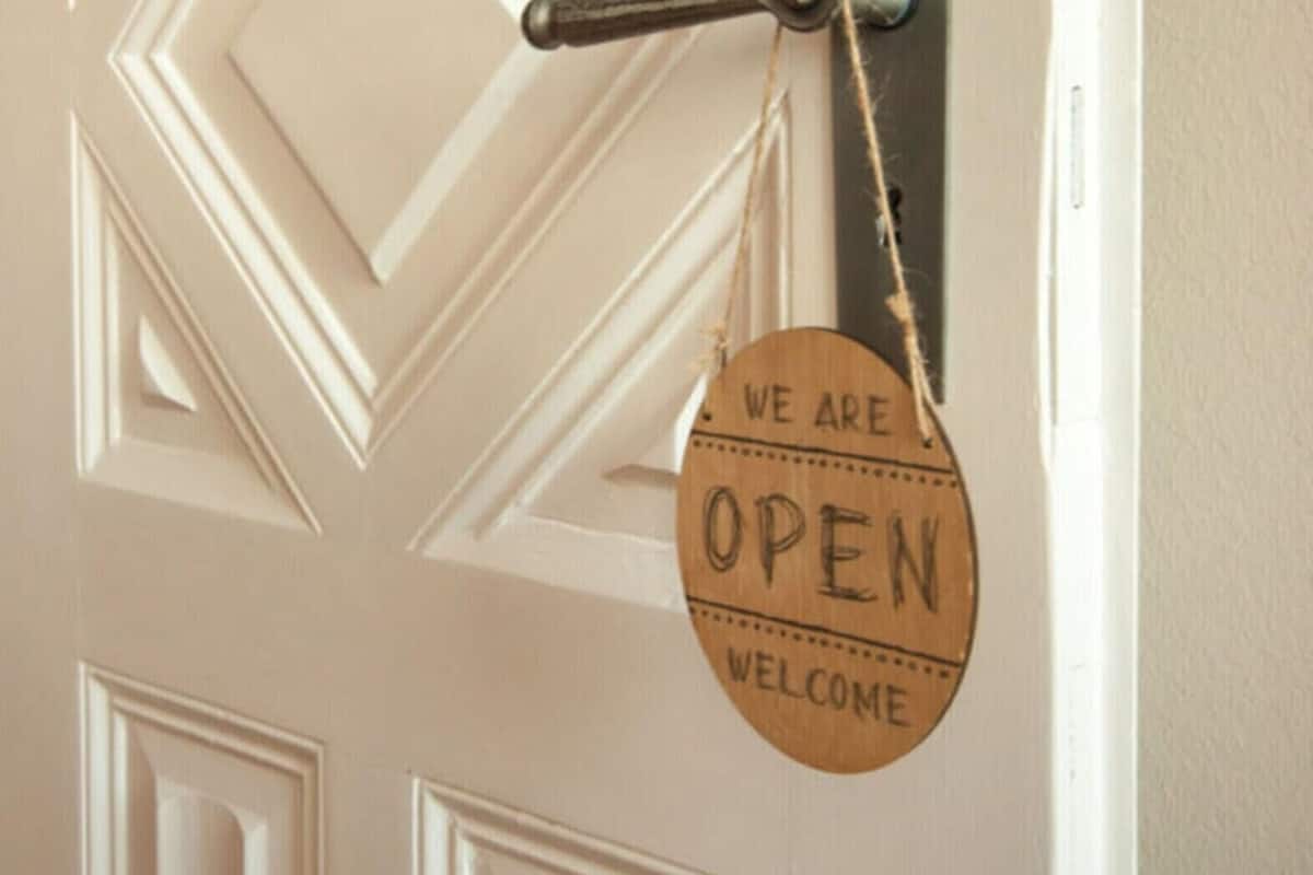 Una puerta con un diseño geométrico y un letrero que dice "WE ARE OPEN WELCOME".